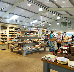 Image shows the farm shop at Denstone Hall, with shelves full of locally-sourced produce and visitors having a good chat